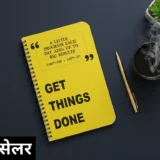 A top-down view of a clean, modern workspace with a dark surface. A bright yellow notebook sits prominently in the center, featuring bold text that reads “GET THINGS DONE,” along with a motivational quote about small daily progress leading to big results. To the right are a steaming cup of black coffee, a gold pen, and a small potted succulent. In the bottom-left corner, an overlay in Hindi reads “#1 बेस्ट सेलर,” indicating a best-selling product or theme of productivity and success.